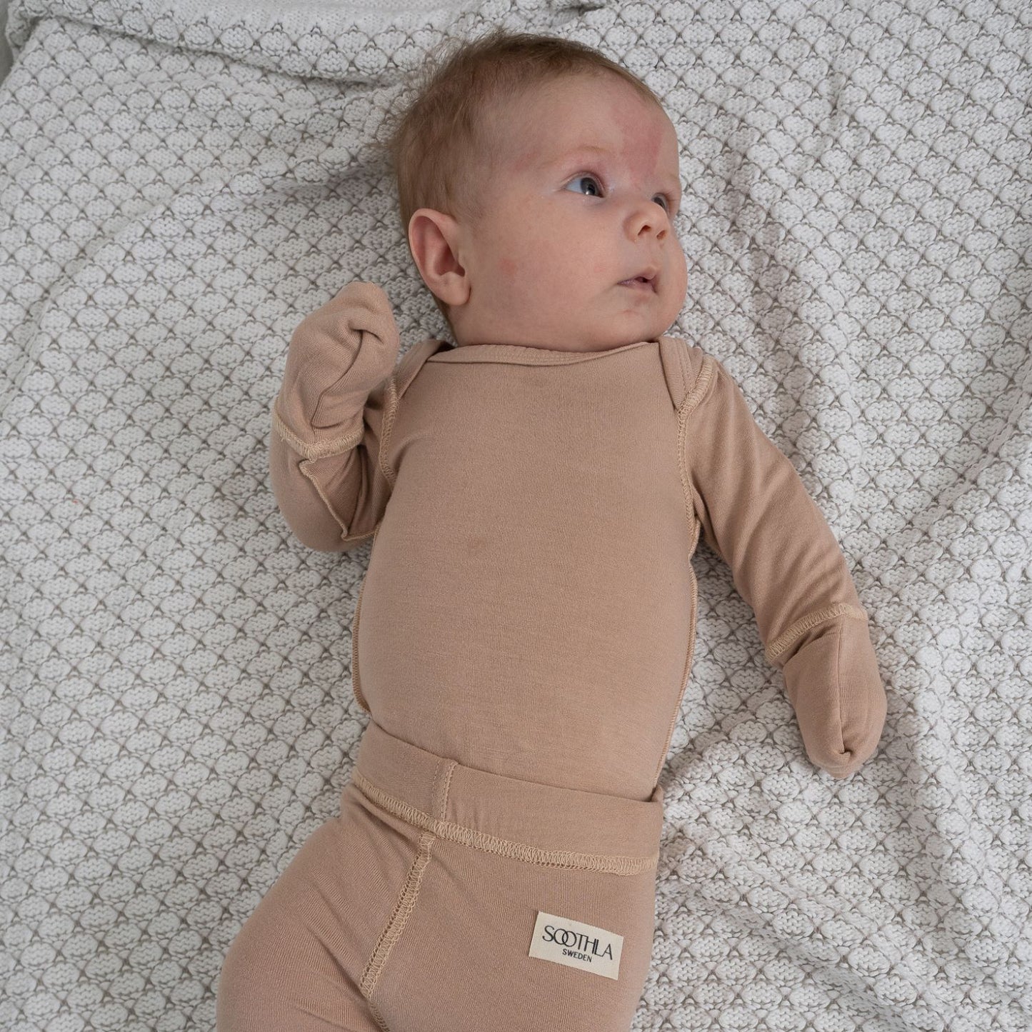 Baby With Eczema On Face Wearing Baby Allergy-friendly Baby Bodysuit From SOOTHLA In Mahogany Rose.